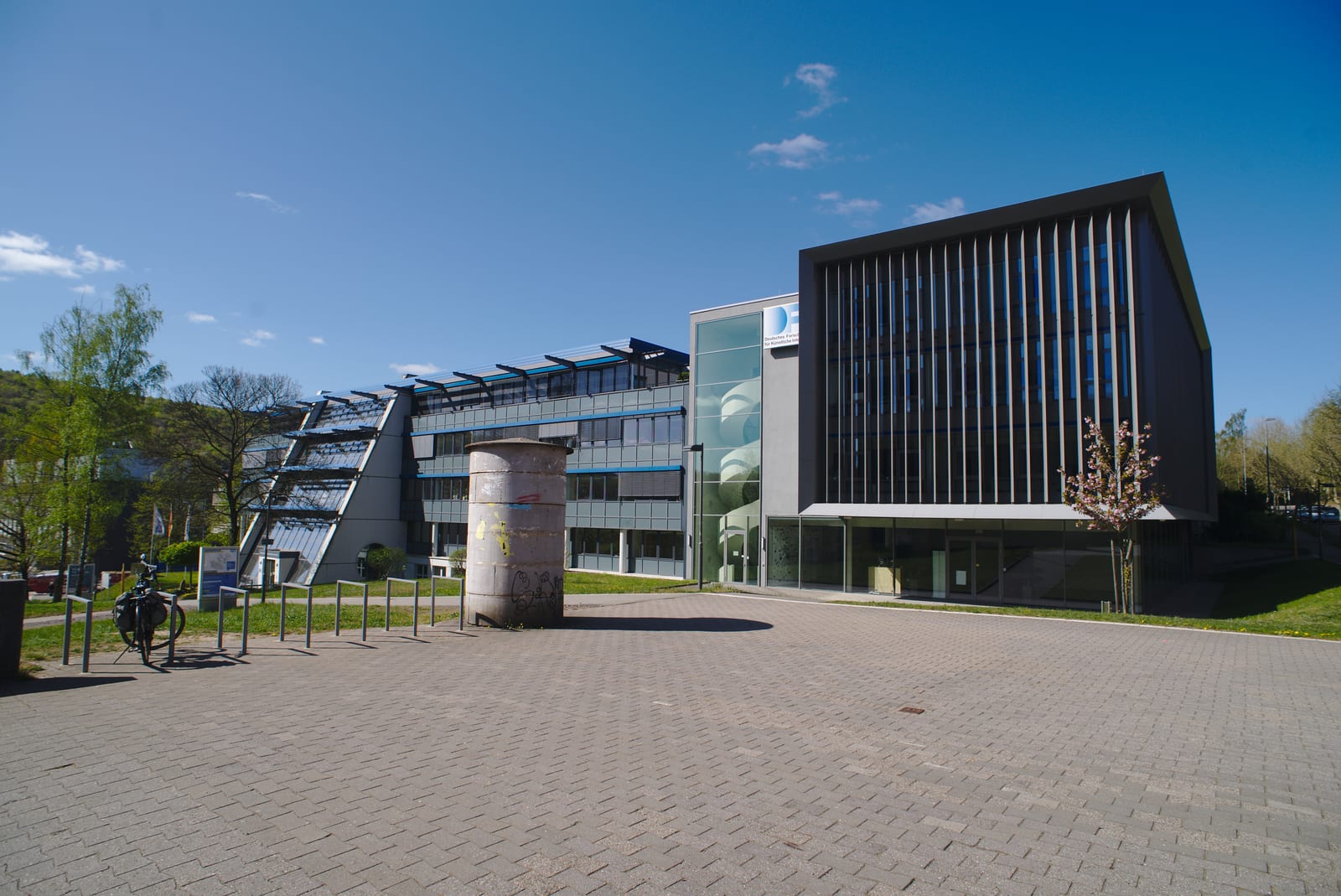 Der Campus der Universität des Saarlandes während eines notwendigen Besuchs in der Zeit des COVID-19 lockdowns. Den Campus so leer vorzufinden ist sonst eine Seltenheit, wenn nicht sogar unmöglich. Auf dem Bild zu sehen sind Gebäude des Deutschen Forschungszentrum für Künstliche Intelligenz und eine leere Litfaßsäule von dem Eingang des Mensagebäudes aus.